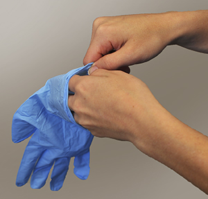 Primer plano de manos colocándose guantes quirúrgicos.