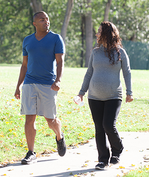 Mujer embarazada y hombre paseando por el parque.