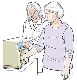 Proveedora de atención médica que le hace una densitometría a una mujer. La mano de la mujer está en una máquina pequeña.
