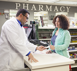 Un farmacéutico habla con una mujer en el mostrador de la farmacia.