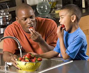 Hombre y niño comiendo fresas.
